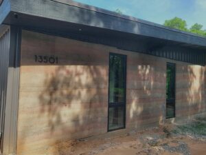 An image of the rammed earth home with street address.