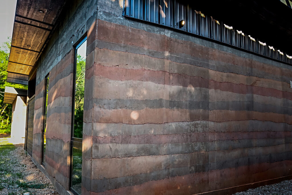 An exterior rammed earth wall with windows.